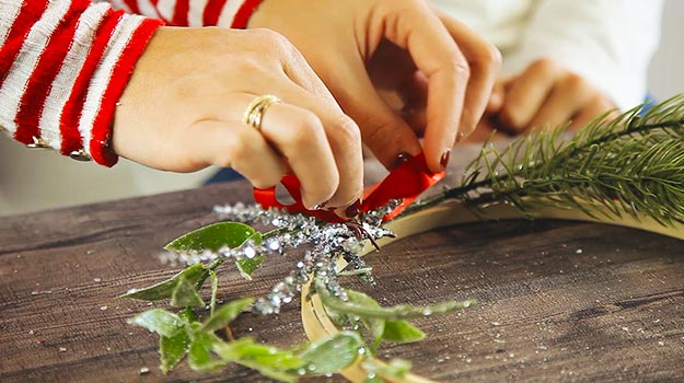 Faire un joli noeud avec du ruban et le coller entre les branches décoratives. 