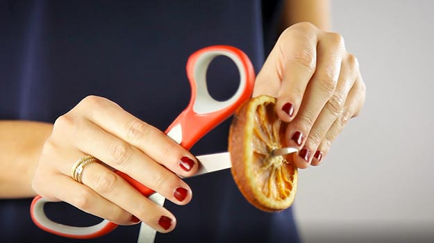 Make a hole with your scissors in the center of the orange