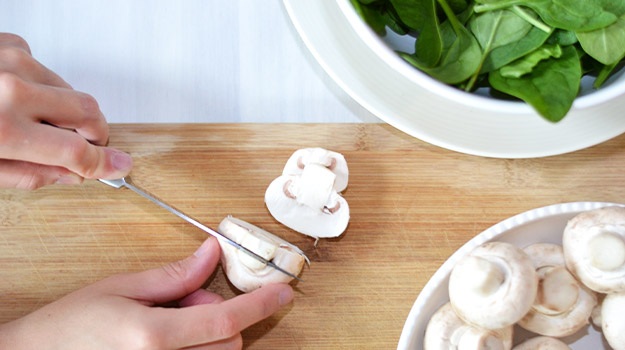 A hand cutting mushroom